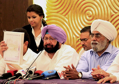 Congress candidate Capt. Amarinder Singh and Prime Minister Manmohan Singh's brother Surjit Singh Singh Kohli addresses a press conference in Amritsar on Saturday. PTI Photo