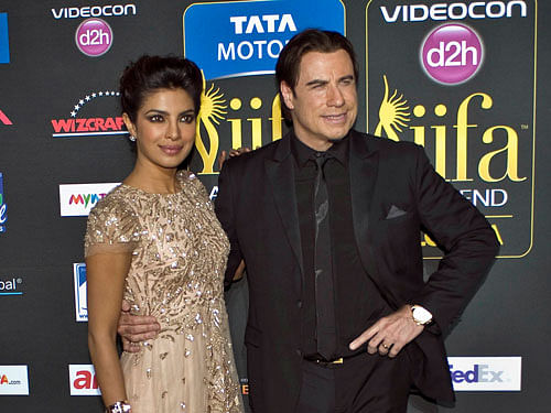 Indian film star Priyanka Chopra (L) poses with American actor John Travolta (R) on the green carpet as they arrive for the 15th annual International Indian Film Awards in Tampa, Florida, April 26, 2014.  AP Photo