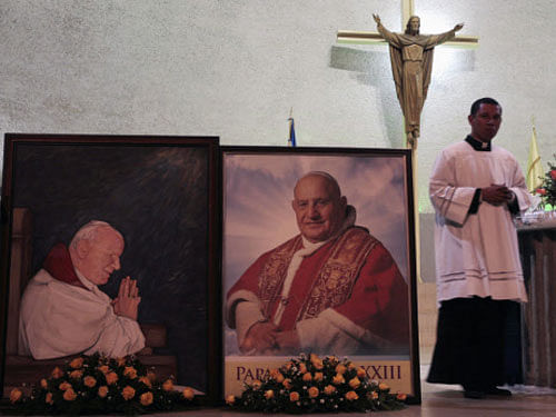 A priest walks past pictures of Pope John Paul II and Pope John XXIII (R) during a mass at the Metropolitan Cathedral l in Managua April 26, 2014. Pope John XXIII, who reigned from 1958 to 1963 and called the modernizing Second Vatican Council, and Pope John Paul II, who reigned for nearly 27 years before his death in 2005 and whose trips around the world made him the most visible pope in history, will be declared saints by Pope Francis at an unprecedented twin canonization on Sunday. REUTERS