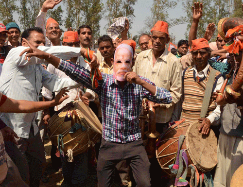 putting a modi face on: A BJP supporter wears a Narendra Modi mask during an election campaign rally in Dehradun on  Tuesday. PTI
