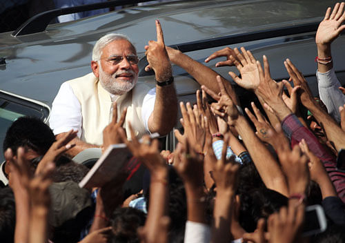 Bharatiya Janata Party's prime ministerial candidate Narendra Modi displays his inked finger to supporters after casting his vote in Ahmadabad, Wednesday, April 30, 2014.