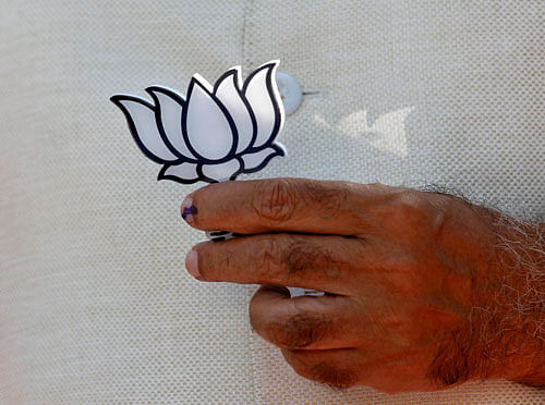 Hindu nationalist Narendra Modi holds cut-out of Lotus after casting his vote at a polling station in Ahmedabad. Reuters Image