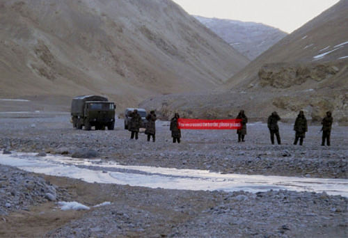 Chinese troop hold a banner which reads, 'You've crossed the border, please go back,' in Ladakh, India. AP file photo