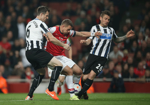 Arsenal's Lukas Podolski, center, holds off the challenge of Newcastle's Mike Williamson, left and Mathieu Debuchy during their English Premier League soccer match between Arsenal and Newcastle United at the Emirates stadium in London, Monday. AP Photo