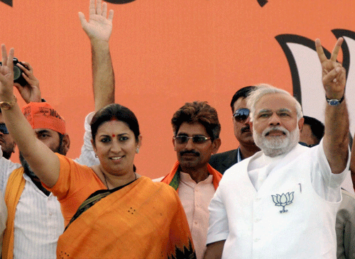 BJP PM candidate Narendra Modi with party candidate Smriti Irani flashes victory sign during an election rally in Amethi on Monday. PTI Phot