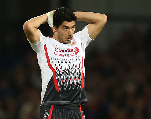 Distraught Liverpool striker Luis Suarez was helped from the Selhurst Park pitch by captain Steven Gerrard on Monday with his shirt pulled over his head to hide his emotions after a day billed as redemption ended in title concession. / AP Photo