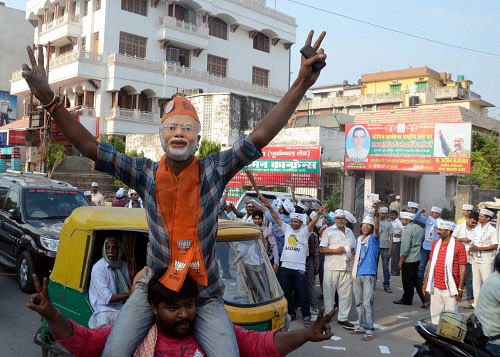 A BJP supporter, dressed up like Narendra Modi, flashes victory sign as AAP supporters at Sigra in Varanasi on Tuesday. PTI Photo