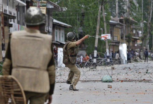 A policeman throws a stone towards Kashmiri protesters during an anti-election protest in Baramulla district on Wednesday. REUTERS