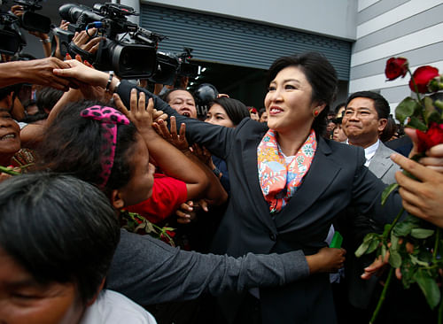 Thailand's Prime Minister Yingluck Shinawatra greets her supporters as she leaves the Permanent Secretary of Defence office in Bangkok May 7, 2014. A Thai court found Yingluck guilty of violating the constitution on Wednesday and said she had to step down, throwing the country into further political turmoil, although ministers not implicated in her case can remain in office. REUTERS