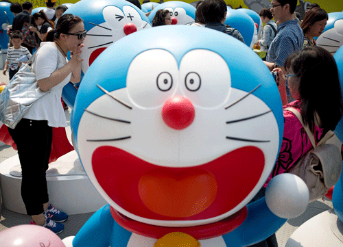 A woman takes a souvenir photo with models of Doraemon, one of Japan's most popular animation characters, during the '100 Doraemon Secret Gadgets Expo' held outside a shopping mall in Beijing, China Wednesday, April 30, 2014. The expo displaying 100 life-sized Doraemon models with different gestures and facial expressions, runs until June 22. AP