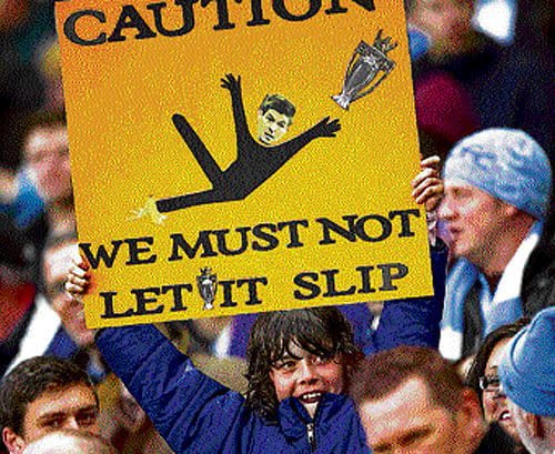 watch out A Manchester City fan holds a placard that not only mocks Liverpool captain Steven Gerrard's mighty slip against Chelsea but also sends out a warning for his team. ap