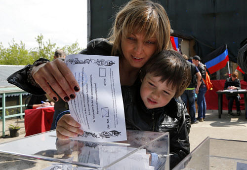 An Ukrainian woman and her son, who are in Russia at the moment, cast a referendum ballot in Moscow, Russia, on Sunday, May 11, 2014. Residents of two restive regions in eastern Ukraine cast ballots Sunday in referendums, which seek approval for declaring sovereign people's republics in the Donetsk and Luhansk regions. Many of Ukrainians living in Moscow came to vote as well. (AP Photo)