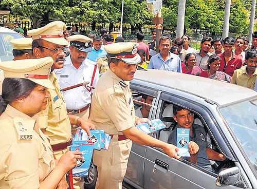 get strapped: Police&#8200;Commissioner M&#8200;A&#8200;Saleem hands over a brochure on the importance of wearing seat belts for car drivers, marking the launch of the drive in front of the Palace, in Mysore, on Wednesday. DCPs Kala Krishnaswamy (Crime and traffic) and A&#8200;N&#8200;Rajanna (Law and order) and others are seen. DH Photo