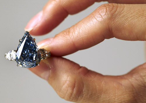 A staff member poses with 'The Blue' diamond during an auction preview for Christie's in Geneva May 9, 2014. The largest flawless vivid blue diamond in the world, weighing 13.22 carats, is expected to reach between CHF 19,000,000 and 23,000,000 (USD 21,000,000 to 25,000,000) when it goes on sale at an upcoming Magnificent Jewels sale in Geneva May 14, 2014. REUTERS