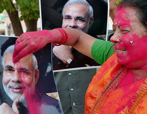 A BJP worker applying gulaal to Nerendra Modi's picture celebrating the party's victory in Lok Sabha polls, in Bikaner on Friday. PTI Photo