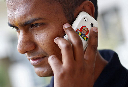 A man speaks on his mobile phone with an image of Modi,  outside the party headquarters in New Delhi. Reuters