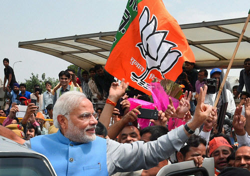 Prime Minister-elect Narendra Modi waves victory sign to the cheering crowd on his arrival at the IGI Airport in New Delhi on Saturday. PTI Photo
