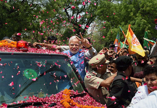 Prime Minister-elect Narendra Modi waves victory sign to the supporters during a road show after his arrival in New Delhi on Saturday. PTI Photo