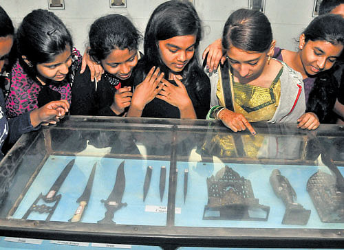 Students take a look at the artefacts on display at an exhibition to mark  International Museum Day at the Venkatappa Art Gallery in the City on Sunday. DH photo