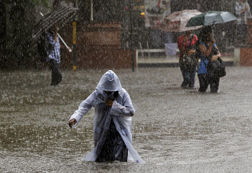 A girl wearing a raincoat wades through a flooded street as it rains in Mumbai, India, Friday, July 12, 2013. AP