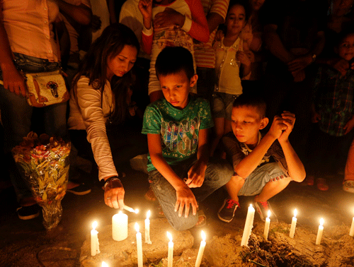 Relatives and residents light candles, in memory of the children who died in a burning bus, at the site of the accident in Fundacion, northern Colombia, May 19, 2014. Thirty-one children and one adult were killed in Colombia on Sunday when fuel exploded on a broken-down bus returning from a church event, an emergency response coordinator said. REUTERS