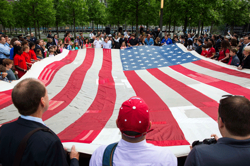 People designated to assist with transferring the National 9/11 Flag, donated by New York Says Thank You Foundation, hold it aloft on the grounds of the 9/11 Memorial Plaza before donating it to the National September 11 Memorial Museum in New York May 21, 2014. Destroyed in the aftermath of the World Trade Center attacks on September 11 the flag has been stitched back together and has visited all 50 states. REUTERS