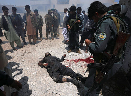 Afghan security forces gather around the body of a Taliban insurgent on the rooftop of a residential building, where insurgents were holed up in, after an attack on the Indian consulate in Herat province May 23 ,2014. A handful of heavily armed insurgents, including suicide bombers, launched the rocket propelled grenade and gun attack on the Indian consulate in Afghanistan's western city of Herat hours before dawn on Friday, officials said. Police said Afghan security forces had killed the attackers, who were holed up in buildings overlooking the consulate, following a firefight that lasted several hours. REUTERS