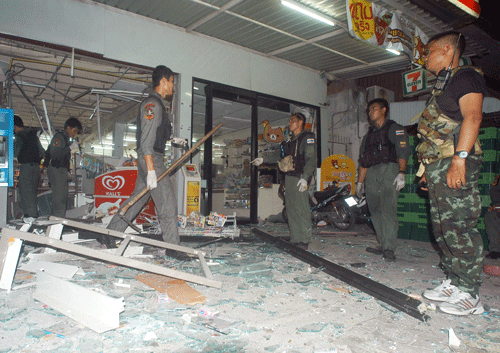 Thai police officers and soldiers examine the site where a bomb exploded at a super store in Pattani province, southern Thailand Saturday, May 24, 2014 Police say at least nine bombs have exploded in Thailand's restive south, killing two people and wounding dozens. The blasts were in a southern province that is facing an Islamic insurgency. AP