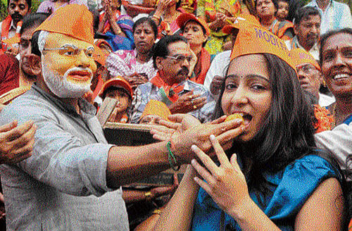 BJP supporters distribute sweets in front of the party office in the City on Monday. Dh photo