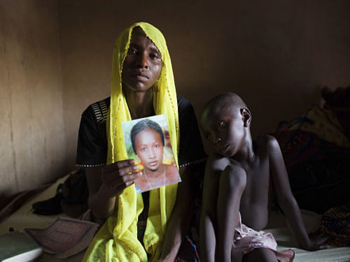 Rachel Daniel, holds up a picture of her abducted daughter Rose Daniel, 17, as her son Bukar sits beside her at her home in Maiduguri. Boko Haram has released four schoolgirls out of more than 200, who have been abducted and held captive since April 14. Reuters photo