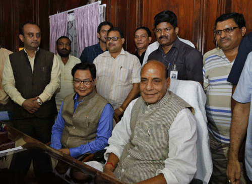 Home Minister Rajnath Singh, sitting right poses for the media with junior minister Kiren Rijiju, sitting left, after taking charge in New Delhi,  AP photo