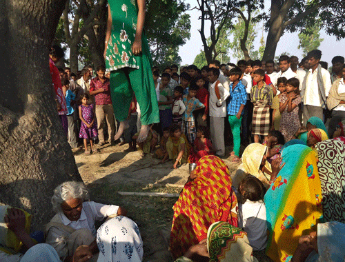 In this Wednesday, May 28, 2014 photograph, villagers gather around the bodies of two teenage sisters hanging from a tree in Katra village in Uttar Pradesh. Two teenage sisters in rural India were raped and killed by attackers who hung their bodies from a mango tree, which became the scene of a silent protest by villagers angry about alleged police inaction in the case. Three of the four men arrested so far are police officers.  AP