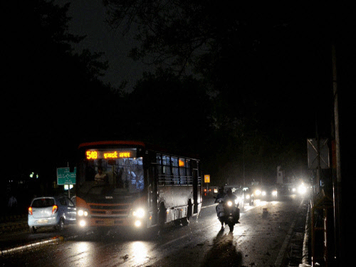 Vehicles plying with their headlights on during a dust storm accompanied by dark clouds in New Delhi. PTI photo
