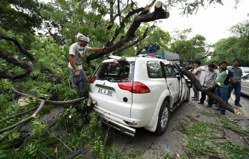 A tree branch fell on a car near Gymkhana Club after a storm accompanied by dark clouds in New Delhi on Friday. PTI Photo
