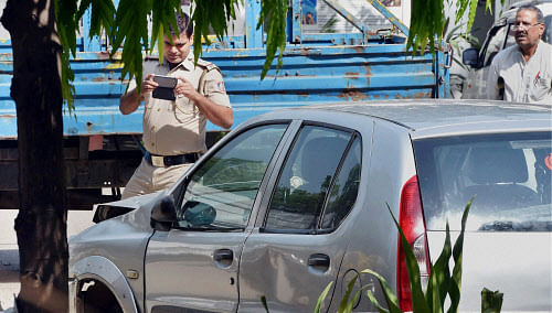 Police officials take photo of the Indica car at Tuglak Road police station which hit Rural Development Minister, Gopinath Munde's car leading to his death in New Delhi on Tuesday. PTI Photo by Vijay Verma