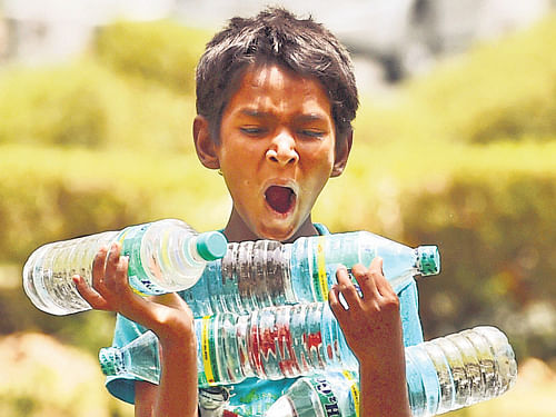 A child carries water bottles to sell on a hot day near Rajpath in New Delhi on Saturday. PTI
