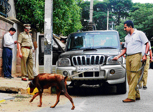 Looking for clues: A police dog is taken around the SUV in which Raghavendra (inset) shot himself dead, near Taralabalu Kendra in RT Nagar on Monday. dh photo