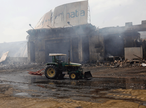 A tractor runs past a damaged building on the tarmac of Jinnah International Airport, after Sunday's attack by Taliban militants, in Karachi June 10, 2014. Taliban militants disguised as security forces stormed into Pakistan's busiest airport on Sunday night, triggering an all-night battle in which at least 27 people were killed. REUTERS