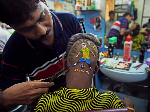 A football fan gets a haircut resembling football star Neymar ahead of the upcoming FIFA World Cup 2014, in Howrah on Wednesday. PTI Photo by Swapan Mahapatra
