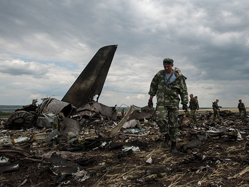 Pro-Russian fighters walk at the site of remnants of a downed Ukrainian army aircraft Il-76 at the airport near Luhansk, Ukraine, Saturday, June 14, 2014. Pro-Russia separatists shot down a Ukrainian military transport plane Saturday, killing all 49 crew and troops aboard in a bloody escalation of the conflict in the country's restive east. AP