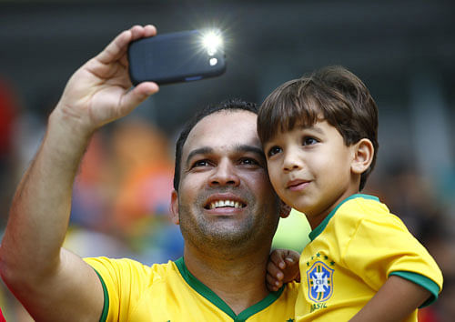 colourful impact: A father-son duo clicks a selfie with the famed Brazilian national team jersey that is adored by millions of football fanatics across the world. Reuters