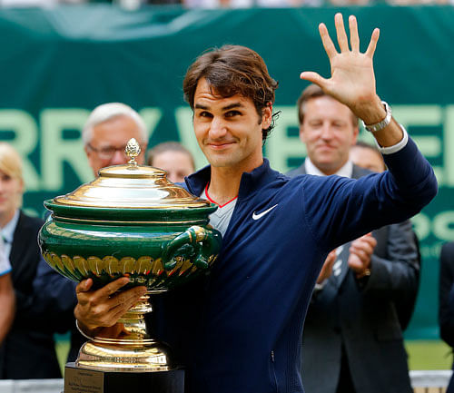 Switzerland's Roger Federer holds the trophy and waves after winning the final of the Gerry Weber Open tennis tournament in Halle, Germany, Sunday, June 15, 2014. Federer beat Colombia's Alejandro Falla 7-6 and 7-6. AP
