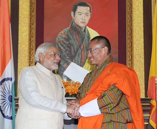 Prime Minister Narendra Modi (L) shakes hands with his Bhutanese counterpart Tshering Tobgay in front of a portrait of Bhutan's King Jigme Khesar Namgyel Wangchuck during their bilateral meeting in Thimphu June 15, 2014. Modi on Sunday kicked off his first visit abroad since taking office, arriving in Bhutan to launch a drive to reassert Indian influence in the region, offering financial and technical help and the lure of a huge market. REUTERS