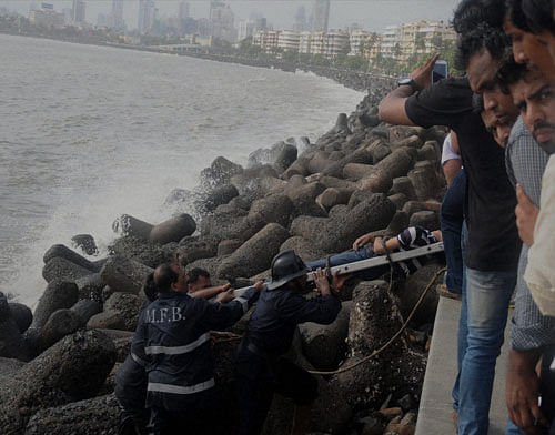 Tragic end: Fire brigade personnel at rescue work after two boys were swept away by huge tidal waves that lashed Marine Drive beach in Mumbai on Sunday. PTI