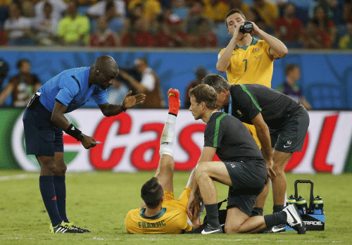 Referee Noumandiez Doue of Ivory Coast (L) gestures near Australia's Ivan Franjic (bottom C) as he lies on the pitch during the team's 2014 World Cup Group B soccer match against Chile at the Pantanal arena in Cuiaba. Reuters photo