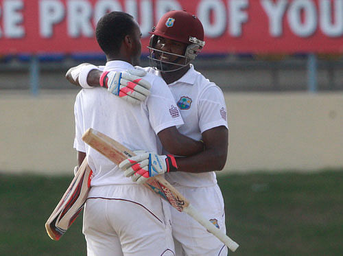 West Indies' batsman Kraigg Brathwaite, left, is hugged by his batting partner Darren Bravo, right, after scoring a half century during the second day of their second cricket Test match against New Zealand in Port of Spain, Trinidad, Tuesday, June 17, 2014. AP
