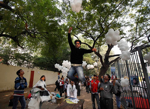 In this Saturday, Nov. 16, 2013 file photo, a Greenpeace activist jumps to catch a thread tied to balloons during a protest against the imprisonment of the group's activists and freelance journalists in New Delhi. India is cracking down on foreign-funded charities after receiving an internal report alleging they are costing the country up to 3 percent of its GDP by rallying communities against polluting industries.