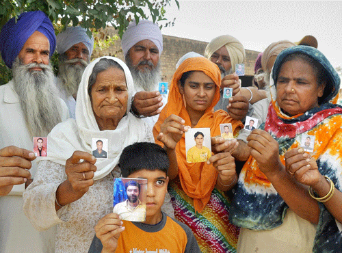 Family members of the lndians trapped in Iraq showing their photographs at a village near Devigarh in Patiala district on Friday. PTI Photo