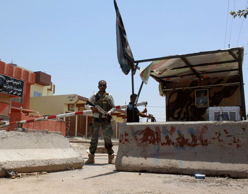 An Iraqi Shi'ite Turkmen fighter stands guard at a checkpoint at Tuz Khurmato in Salahuddin Province. June 28, 2014. Iraqi troops were trying to advance on Tikrit from the direction of Samarra to the south that has become the military's line in the sand against a militant advance by the radical Sunni Islamic State in Iraq and the Levant (ISIL) group southwards towards Baghdad. REUTERS