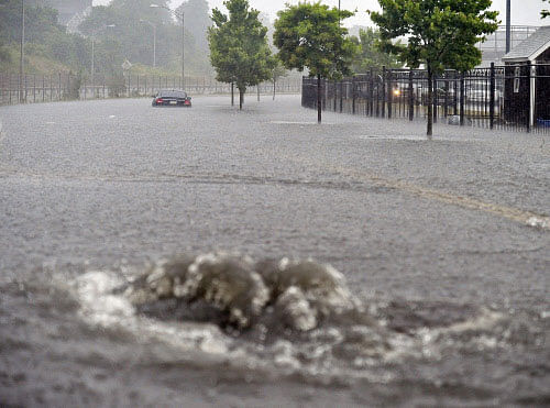 As a water drain overflows a vehicle sits in the flooded waters on Friday, July 4, 2014, in New Bedford, Mass., after heavy rains from Hurricane Arthur. AP photo